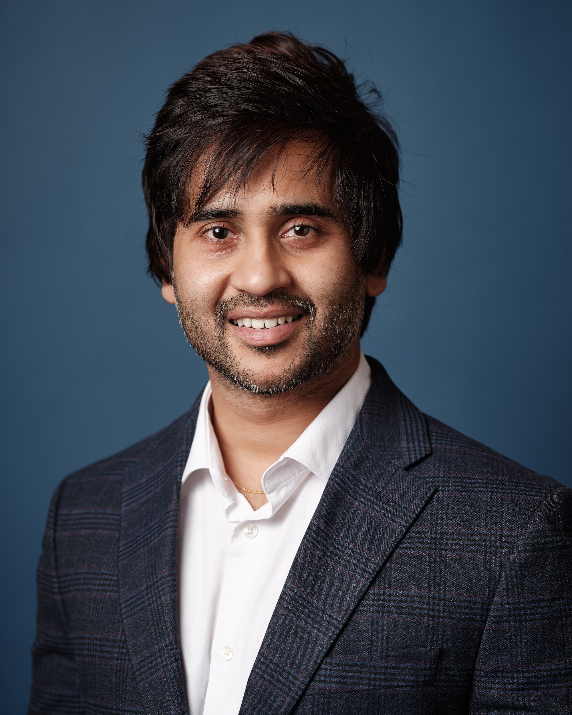 Head shot of Anudeep Bathula with white shirt and navy patterned jacket.