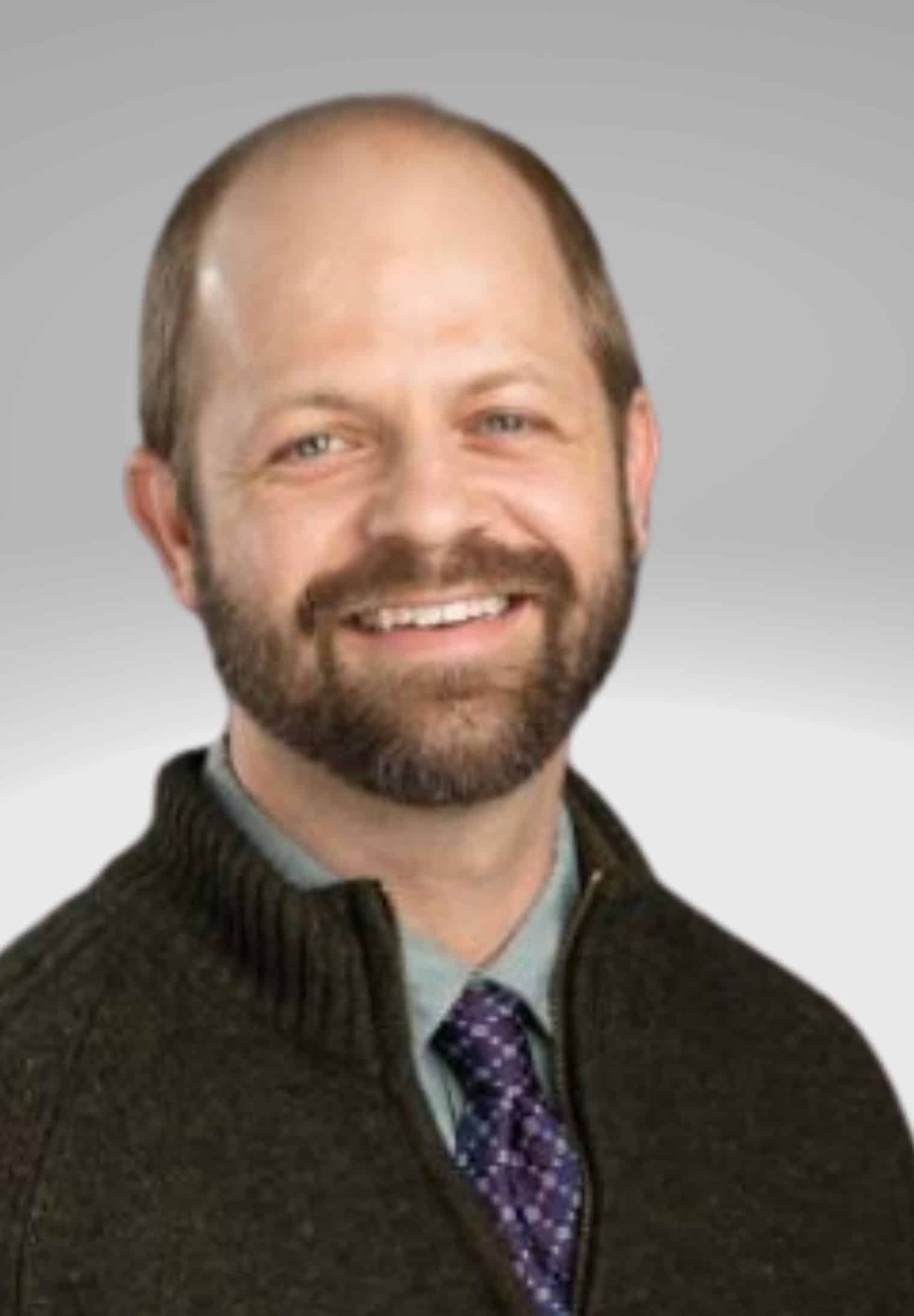Head shot of Jeffrey Kauppi wearing a dark sweater, in front of a light gray background.