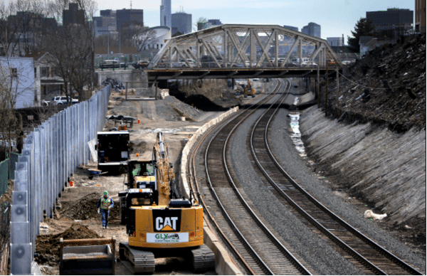 Green Line Northwest Extension rail corridor construction with CAT equipment and retaining wall installation.