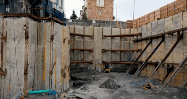 Excavation with steel bracing and shotcrete shoring at 935 Eglinton Avenue West construction site.