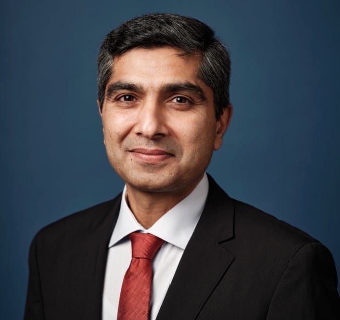 Head shot of Atif Nazir with white shirt, red tie and navy patterned jacket.
